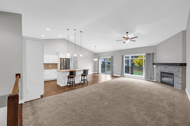 unfurnished living room with ceiling fan, dark hardwood / wood-style floors, vaulted ceiling, and a fireplace