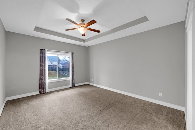 unfurnished room featuring a tray ceiling, carpet, and ceiling fan