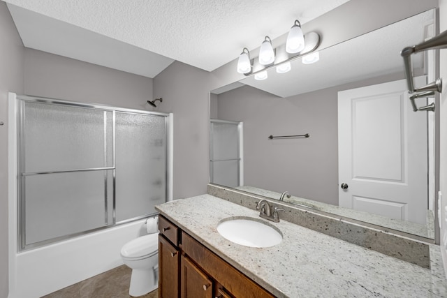 full bathroom featuring vanity, combined bath / shower with glass door, a textured ceiling, and toilet