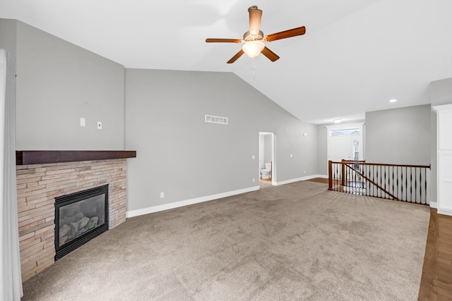 unfurnished living room with ceiling fan, a stone fireplace, carpet, and lofted ceiling