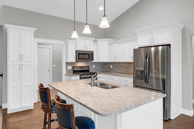 kitchen with hardwood / wood-style floors, white cabinets, a center island with sink, appliances with stainless steel finishes, and sink