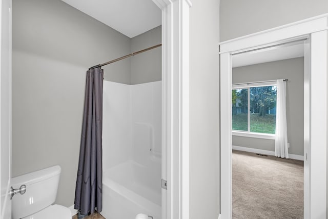 bathroom featuring shower / bath combination with curtain and toilet