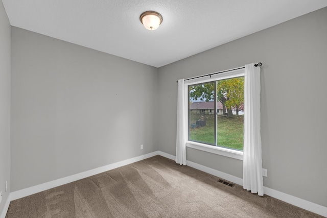 empty room with carpet floors and a textured ceiling