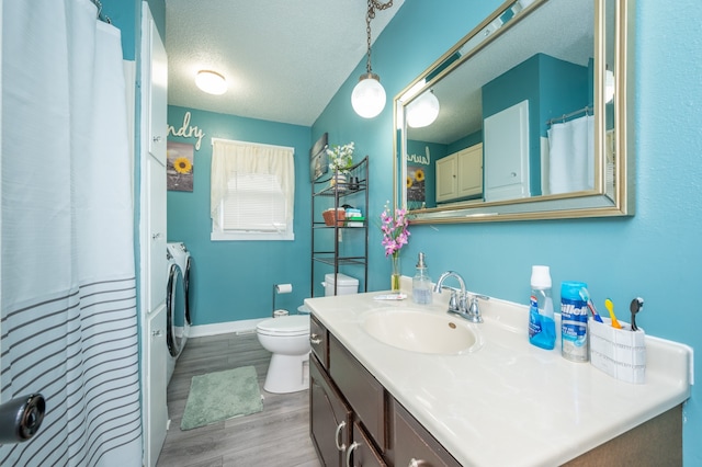 bathroom with a textured ceiling, hardwood / wood-style flooring, separate washer and dryer, toilet, and vanity