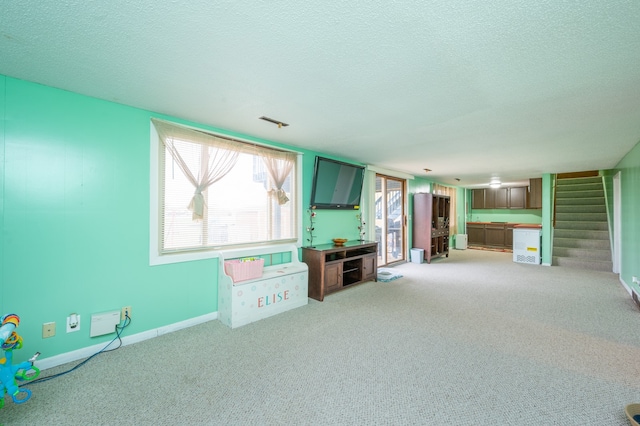 unfurnished living room featuring light carpet and a textured ceiling