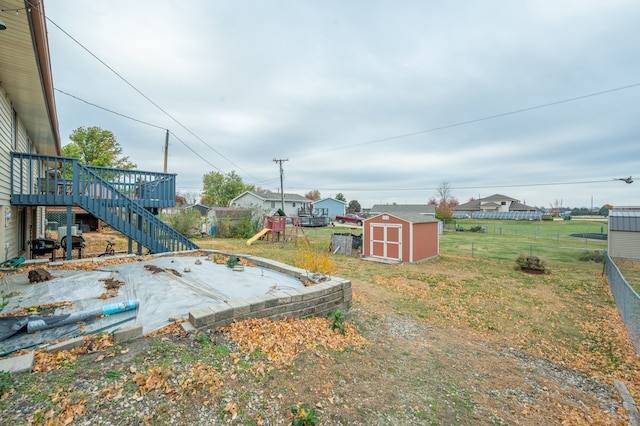 view of yard featuring a wooden deck, a shed, and a playground