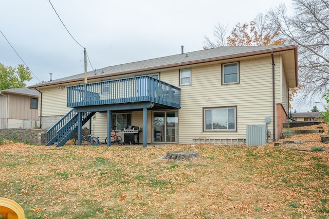 rear view of property featuring a deck, a lawn, and cooling unit