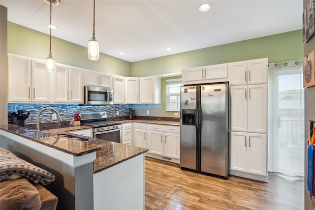 kitchen with pendant lighting, white cabinets, stainless steel appliances, and a healthy amount of sunlight