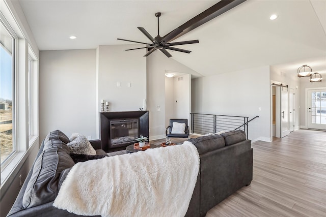 living area featuring vaulted ceiling with beams, recessed lighting, a barn door, light wood-style floors, and baseboards