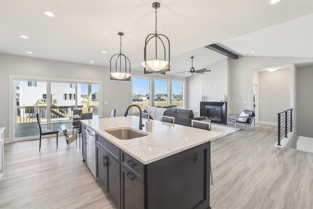 kitchen with light wood finished floors, lofted ceiling with beams, hanging light fixtures, a sink, and recessed lighting