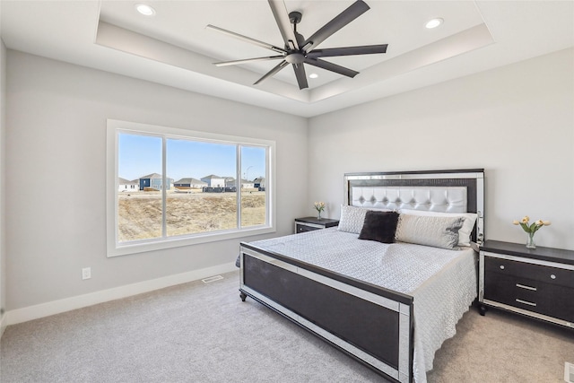 bedroom with a tray ceiling, carpet, and baseboards