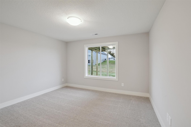 unfurnished room featuring light carpet, baseboards, visible vents, and a textured ceiling