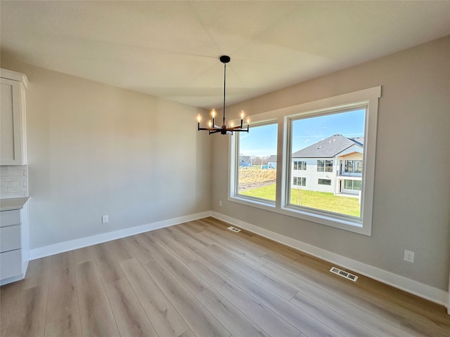 unfurnished dining area featuring a chandelier and light hardwood / wood-style flooring