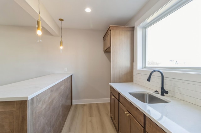 kitchen featuring light stone counters, decorative light fixtures, sink, and tasteful backsplash