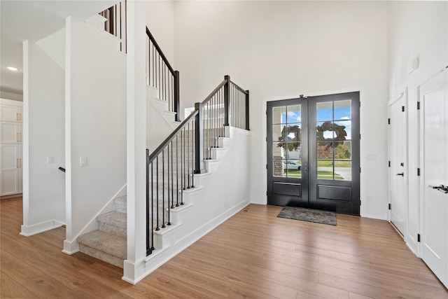 foyer entrance with light hardwood / wood-style floors, french doors, and a high ceiling