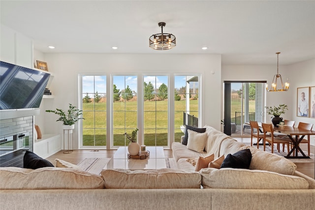 living room with a brick fireplace, an inviting chandelier, and light wood-type flooring