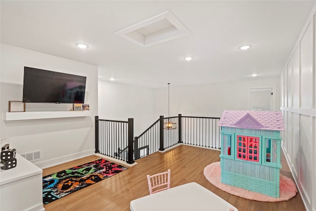 rec room with hardwood / wood-style floors and a notable chandelier