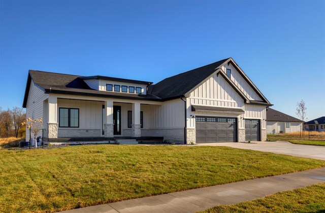 view of front of house with a front yard, covered porch, and a garage