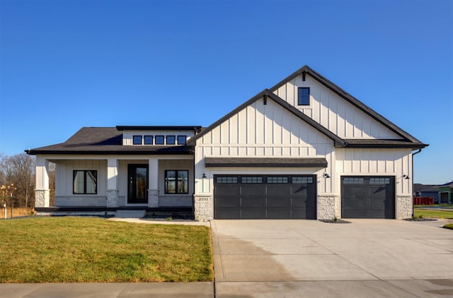 modern farmhouse featuring a garage, driveway, stone siding, board and batten siding, and a front yard