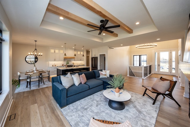 living room featuring beamed ceiling, light hardwood / wood-style floors, and a raised ceiling