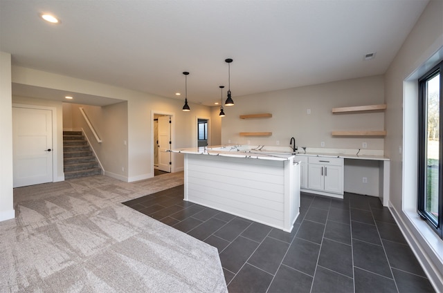 kitchen featuring white cabinetry, a wealth of natural light, decorative light fixtures, and a kitchen island with sink