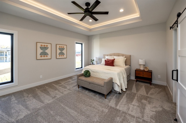 bedroom featuring multiple windows, a barn door, carpet flooring, and ceiling fan