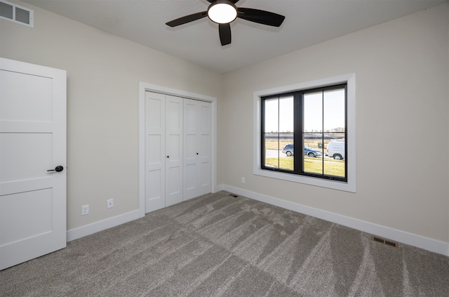 unfurnished bedroom with a closet, light colored carpet, and ceiling fan