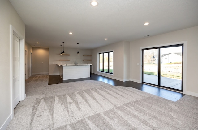 unfurnished living room with indoor wet bar and light colored carpet