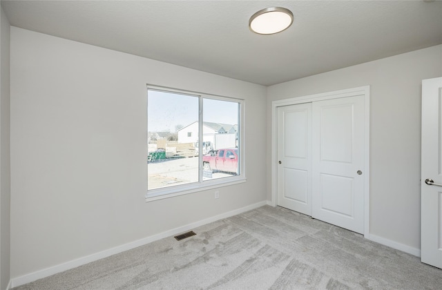 unfurnished bedroom featuring light carpet and a closet