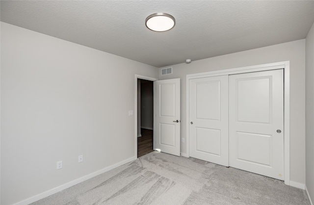 unfurnished bedroom featuring a closet, light carpet, and a textured ceiling