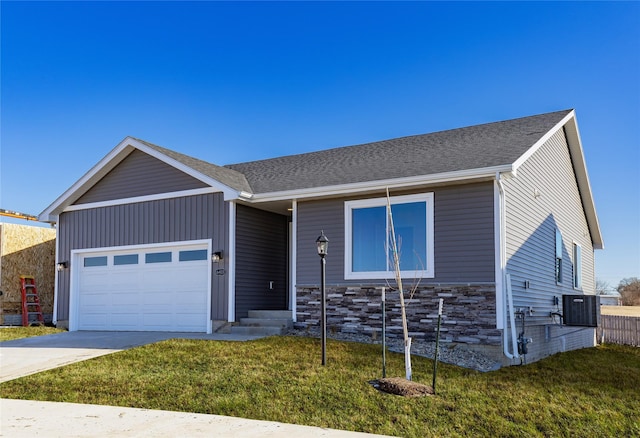 view of front of house featuring a garage, central AC unit, and a front lawn