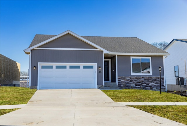 view of front of property featuring a garage, a front lawn, and central air condition unit