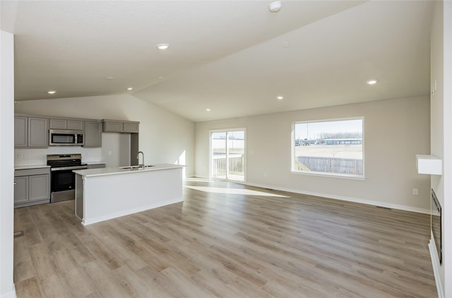 kitchen featuring gray cabinets, sink, backsplash, a kitchen island with sink, and stainless steel appliances