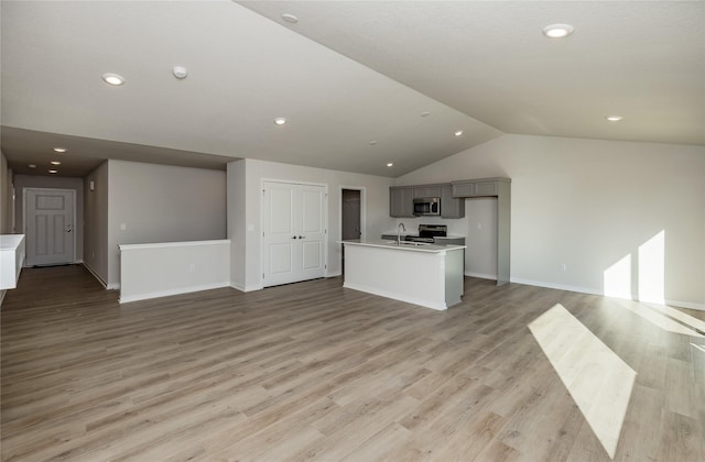 unfurnished living room with sink, light hardwood / wood-style flooring, and vaulted ceiling