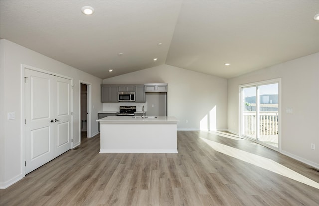 kitchen featuring sink, appliances with stainless steel finishes, gray cabinetry, light hardwood / wood-style floors, and an island with sink