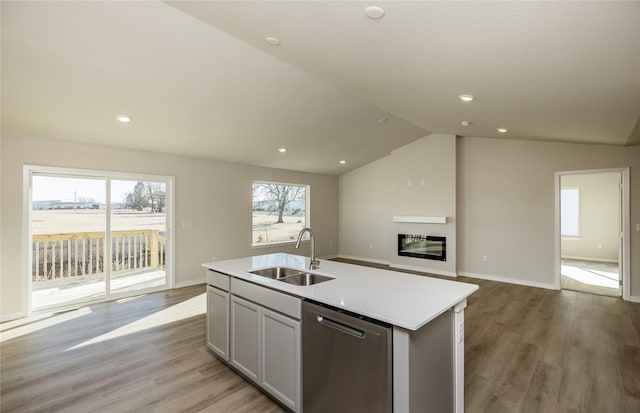 kitchen with sink, light hardwood / wood-style flooring, dishwasher, white cabinetry, and a center island with sink