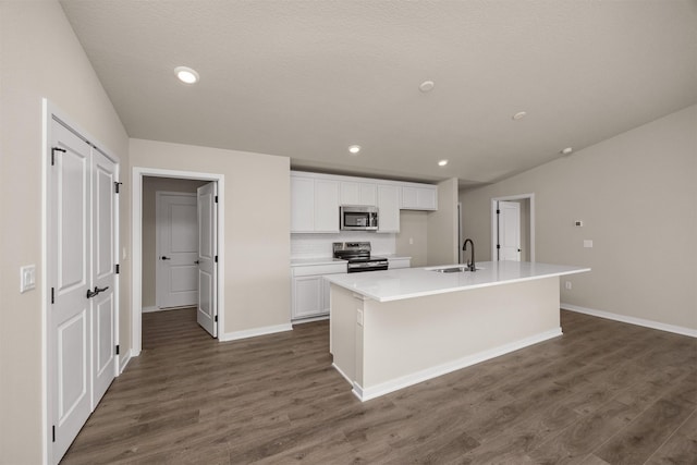9748 Thorton Dr, Johnston, IA 50131 - kitchen featuring appliances with stainless steel finishes, white cabinets, a sink, an island with sink, and dark wood-style floors