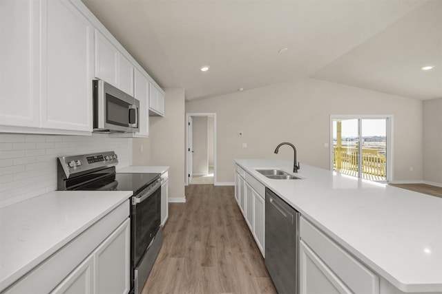 9748 Thorton Dr, Johnston, IA 50131 - kitchen featuring appliances with stainless steel finishes, a sink, backsplash, lofted ceiling, and light wood-type flooring