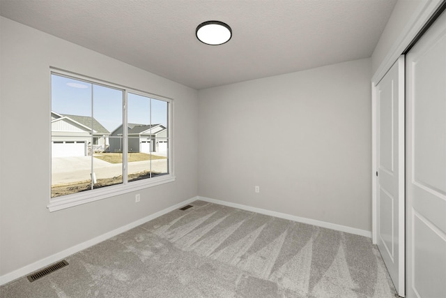 9748 Thorton Dr, Johnston, IA 50131 - unfurnished bedroom featuring a closet, carpet floors, baseboards, and a textured ceiling