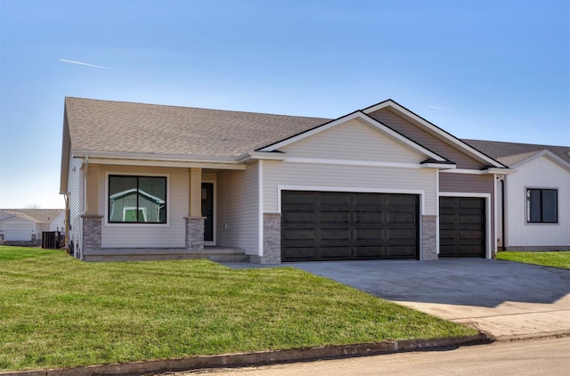 view of front facade with central air condition unit, a shingled roof, concrete driveway, an attached garage, and a front lawn