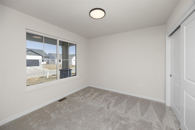 carpeted empty room with visible vents and baseboards