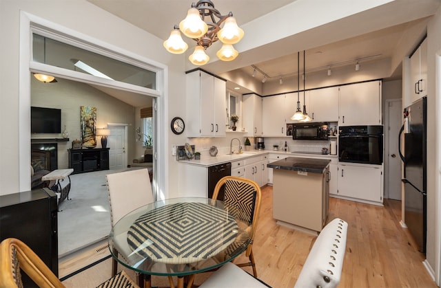 kitchen featuring black appliances, a center island, hanging light fixtures, and white cabinets