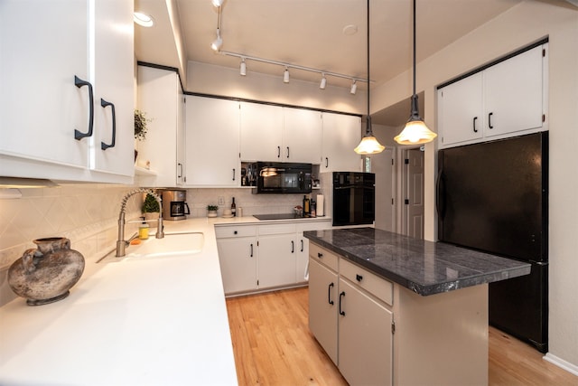 kitchen with decorative backsplash, a kitchen island, white cabinetry, black appliances, and light hardwood / wood-style floors