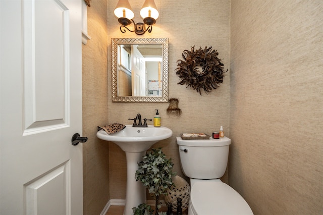 bathroom featuring an inviting chandelier and toilet