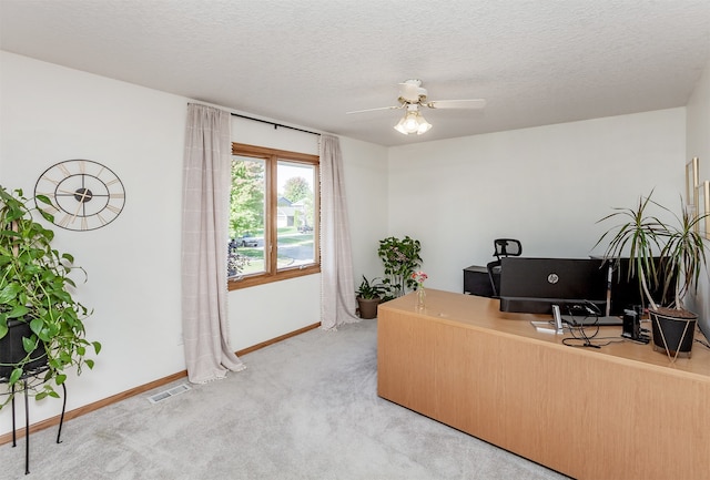 carpeted office space with a textured ceiling and ceiling fan