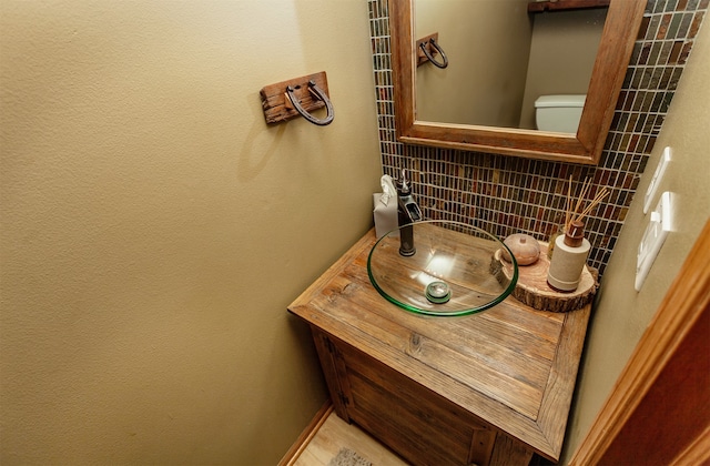 bathroom featuring vanity, toilet, and decorative backsplash