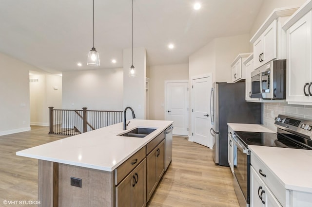 kitchen featuring appliances with stainless steel finishes, a kitchen island with sink, sink, and white cabinets