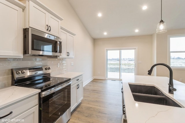 kitchen with light stone countertops, appliances with stainless steel finishes, sink, and white cabinets