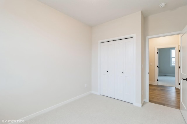 unfurnished bedroom with light colored carpet and a closet