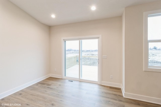 spare room with plenty of natural light and light hardwood / wood-style flooring